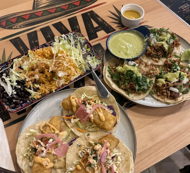 Table of fish and carnitas tacos with Mexican rice and black beans at MEXIKAN in Heritage Valley, Edmonton